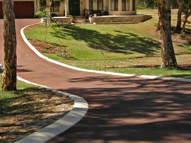 Red asphalt driveway with white kerb.